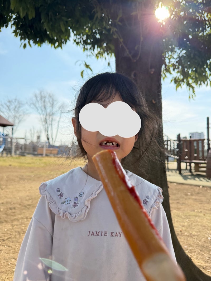 歯茎でフランクフルトを噛む娘の画像