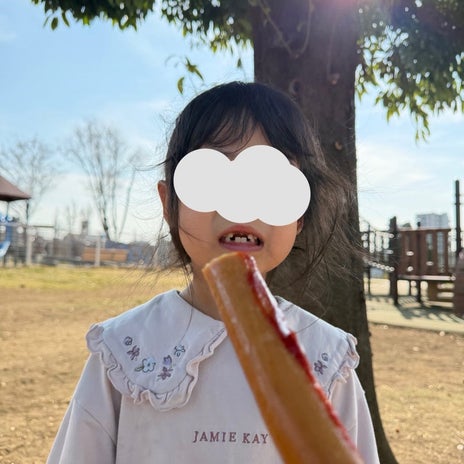 歯茎でフランクフルトを噛む娘の画像